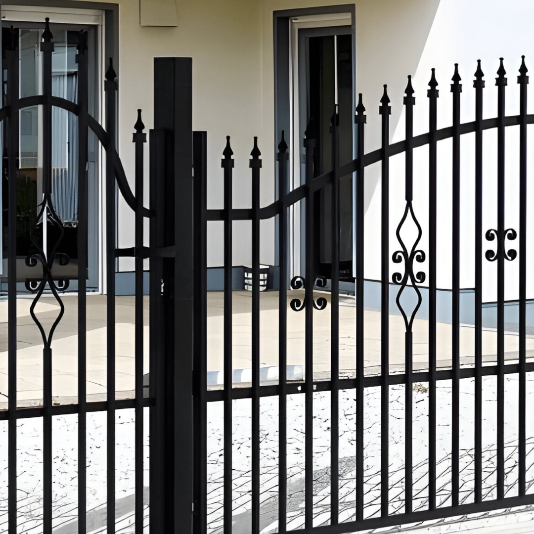 Svart smidesgrind och smidesstaket i modell Boden, monterade vid stolpe framför ett hus